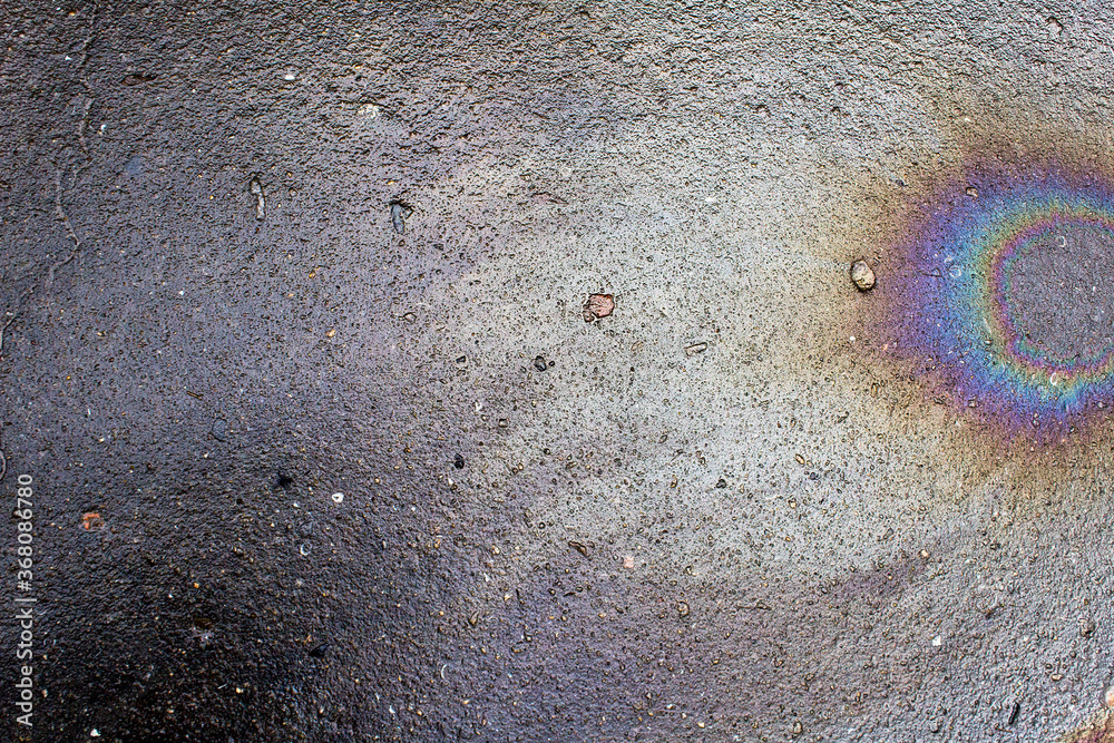 Colorful abstract cosmos comet shape petrol spot on grey city asphalt road 