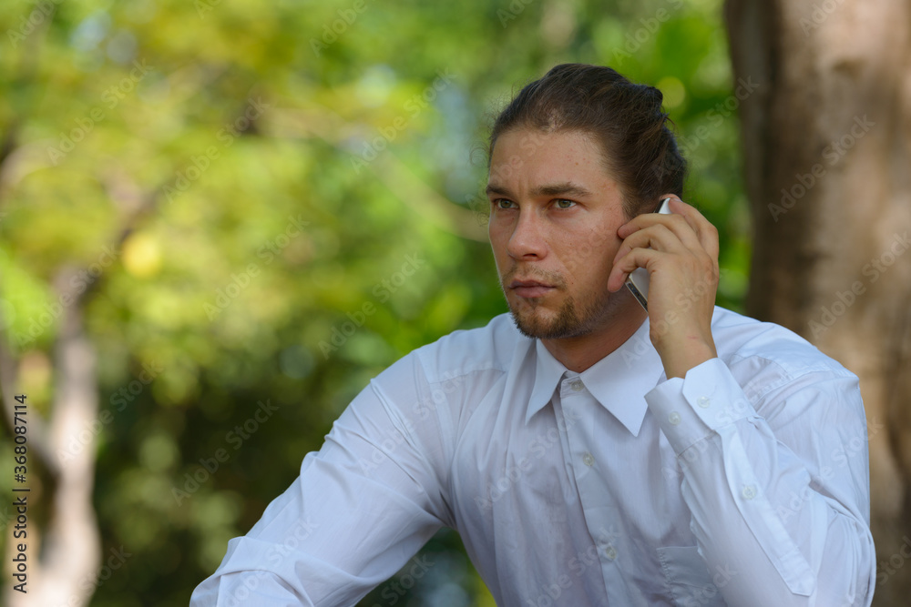 Handsome bearded businessman with long hair at the park Handsome bearded businessman with long hair at the park