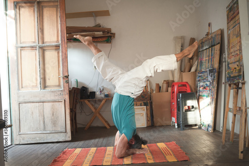 Man doing a variation of the Sirsasana yoga pose indoors