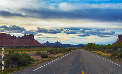 The road passing through the prairie against the backdrop of a mountain landscape.