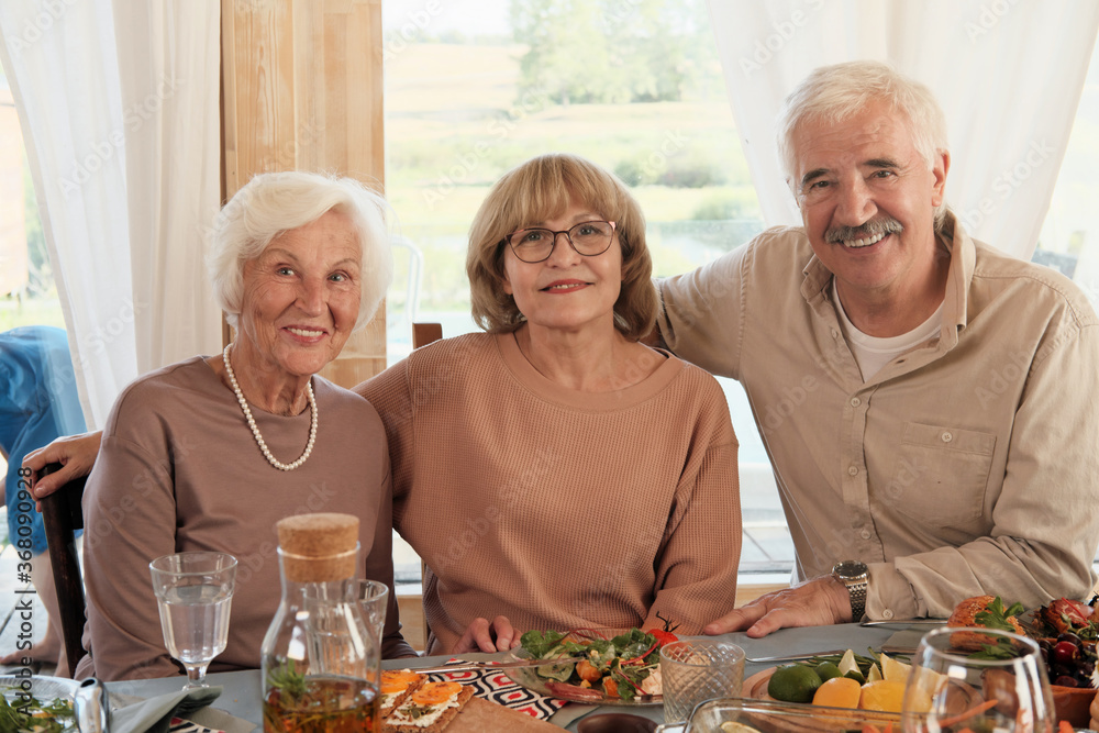 Portrait of senior people smiling at camera while sitting at the dinner table at home Portrait of senior people smiling at camera while sitting at the dinner table at home