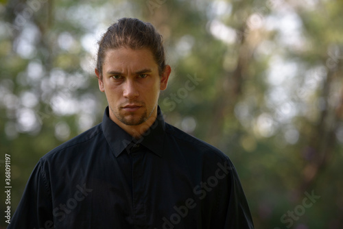 Handsome bearded businessman with long hair at the park