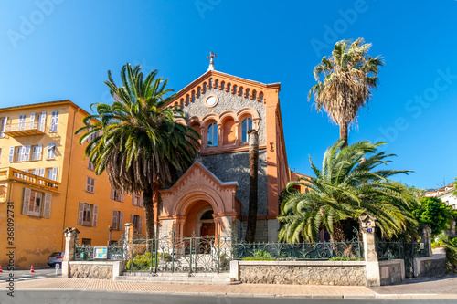 The picturesque Reformed Protestant Church of France surrounded by palm trees in the Mediterranean city of Menton, France.
