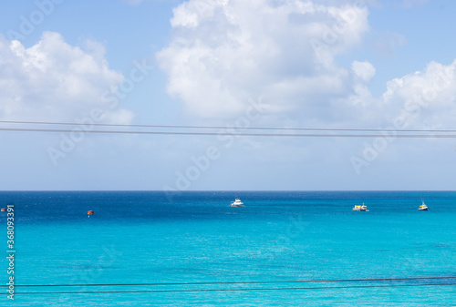 View of Serenity: Beautiful Azure Sea with Small Fishing Boats on Horizon and Blue Sky with White Cloud in Sunny Day. Picturesque Landscape.