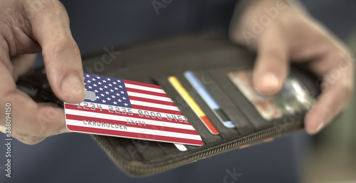 Pulling plastic bank card with flag of the United States out of the wallet, fictional card number