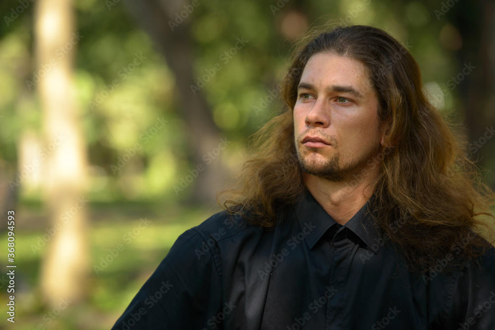 Handsome bearded businessman with long hair at the park Handsome bearded businessman with long hair at the park