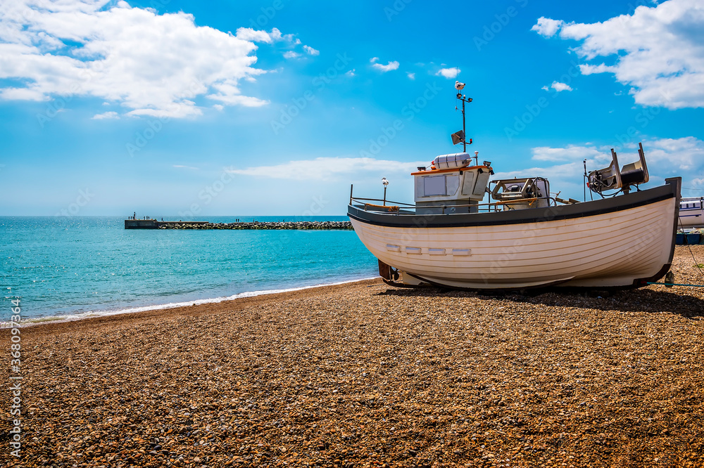 A traditional wooden fishing boat rests at the waters edge in old Hastings, Sussex, UK in summer