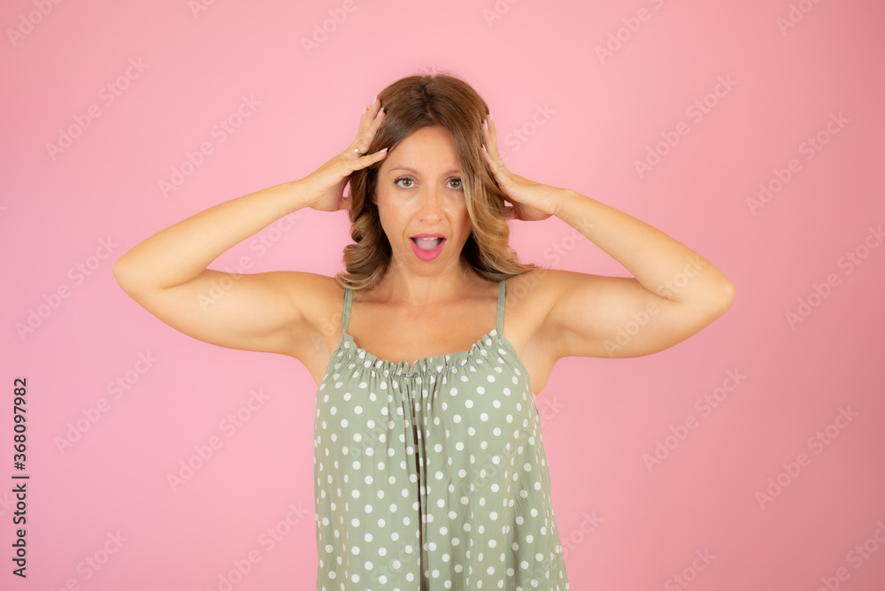 Woman in green dress on pink background gesturing Woman in green dress on pink background gesturing