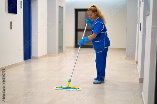 A cleaning lady mops the floor in an office building