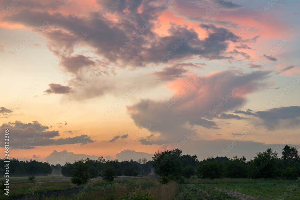 Rural landscape with dramatic clouds over the horizon. Dynamic sky with clouds illuminated by the sun Rural landscape with dramatic clouds over the horizon. Dynamic sky with clouds illuminated by the sun
