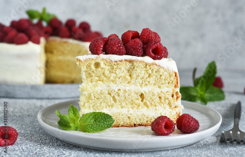 Slice of cake. Birthday cake with cream cheese and raspberries and mint on a concrete kitchen background.