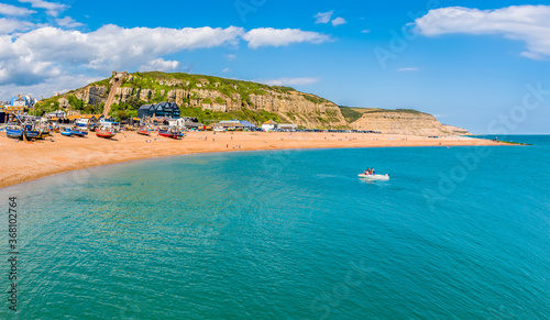 Fototapeta Naklejka Na Ścianę i Meble -  A view from the sea towards the beach and east cliffs in Hastings, Sussex in summer