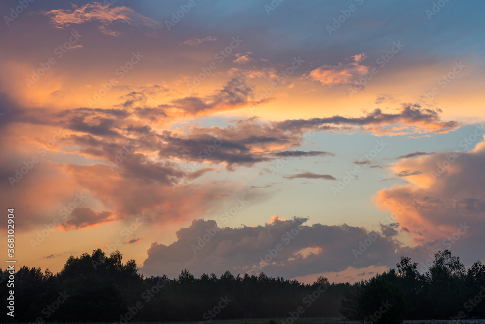 Amazing view of the sky with dramatic clouds illuminated by the sun during sunrise