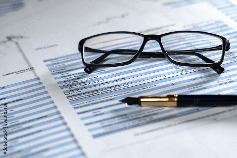 Balance sheet in stockholder report book with glasses and pen, balance sheet is mock-up. Investment analysis for portfolio. selective focus Balance sheet in stockholder report book with glasses and pen, balance sheet is mock-up. Investment analysis for portfolio. selective focus