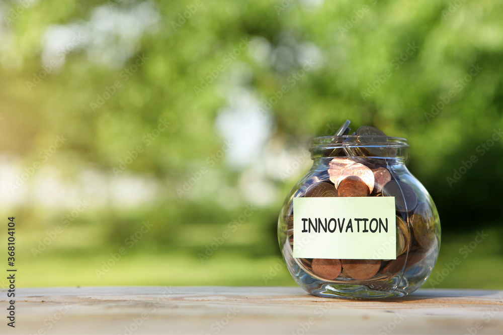 Innovation. Glass jar with coins, on a wooden table, on a natural background.Investment and finance concept.