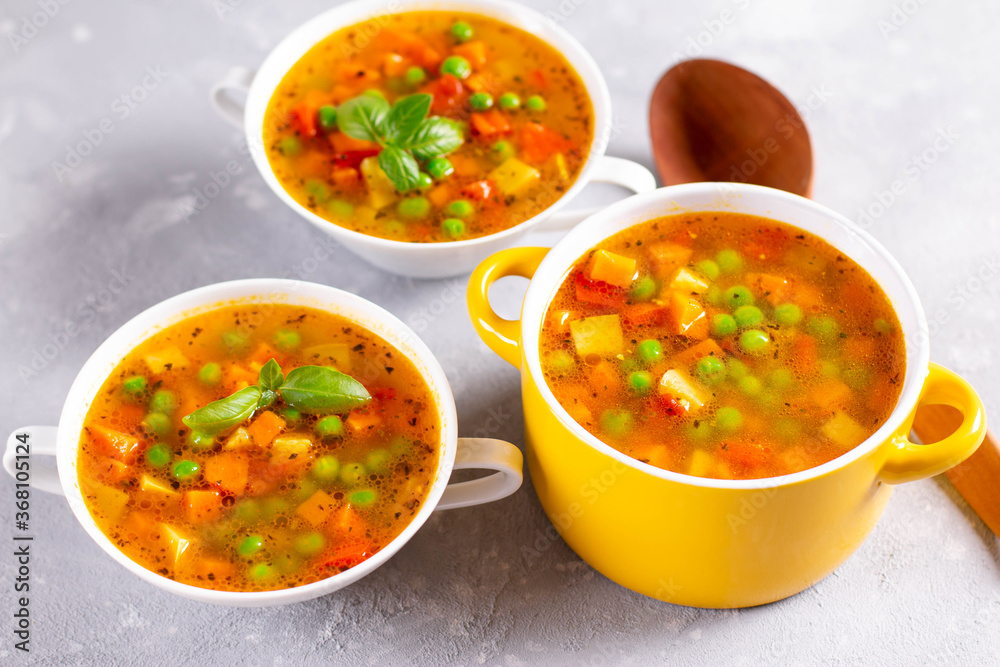 Vegetable soup with spices in a yellow saucepan on a light stone background. Healthy food Vegetable soup with spices in a yellow saucepan on a light stone background. Healthy food