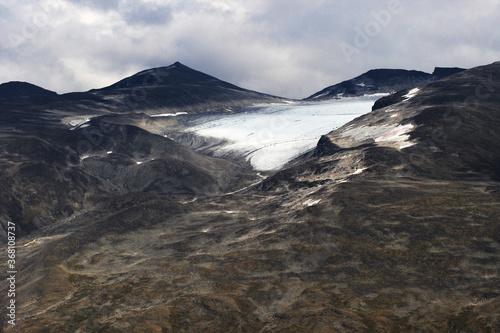A light blue glacier up in the dark Norwegian mountains during summetime.  photo