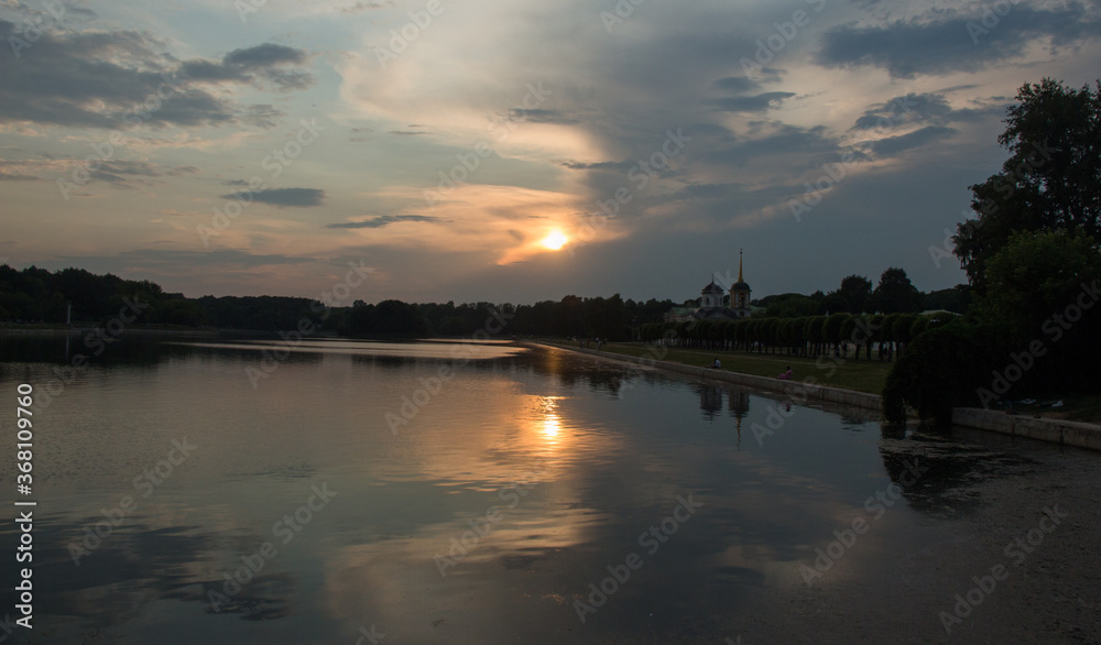 Sunset with clouds and symmetric reflection in lake. Kuskovo park, Moscow, Russia