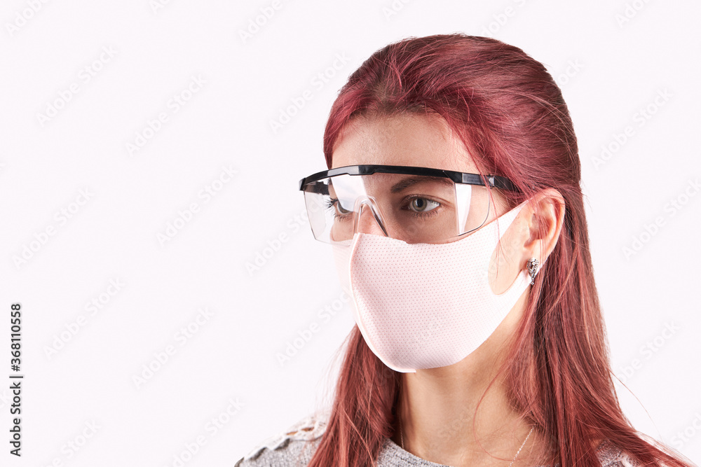 studio portrait of a young caucasian woman wearing protective face mask and goggles. isolated on a gray background. copy space