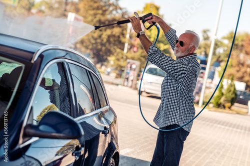 Senior man wash his car.