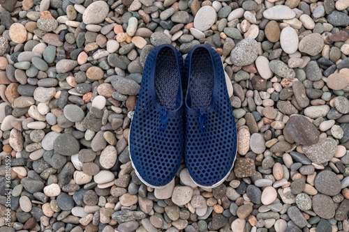 Blue rubber bathing slippers. Beach shoes on pebbles, near the sea.
