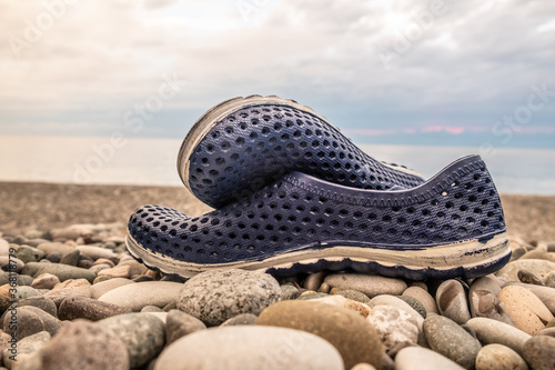 Blue rubber bathing slippers. Beach shoes on pebbles, near the sea.