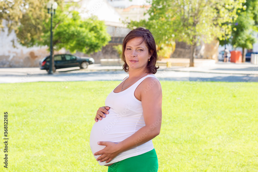 Close up of pregnant belly in nature in a city park Close up of pregnant belly in nature in a city park