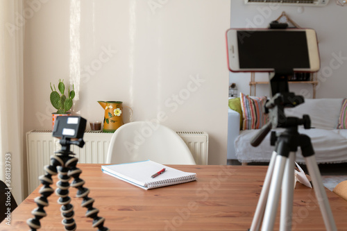 On the table, the camera, the notepad chair and the content producer shoot with a tripod and mobile phone.