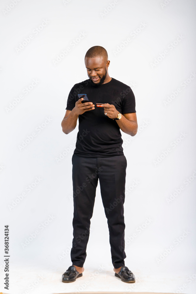 young black handsome man standing using his credit card to pay for something on his smartphone