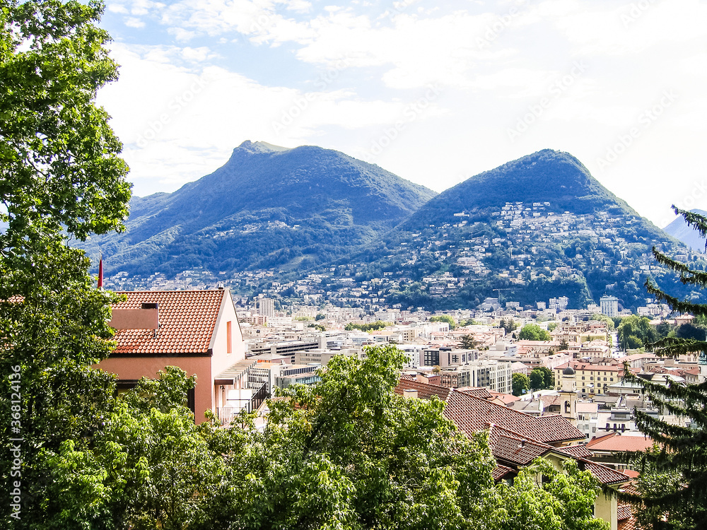 Aerial view of Lugano city with houses and cityscape, and alpine Swiss mountains