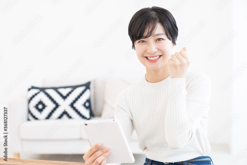部屋でタブレットを見る女性 部屋でタブレットを見る女性