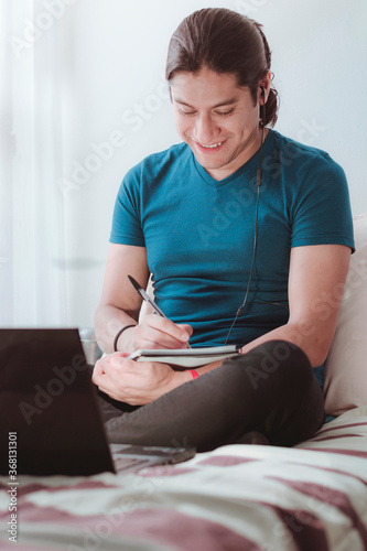 Joven latino trabajando en casa atravez de su computadora photo