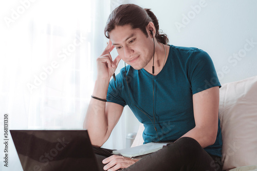 Joven latino trabajando en casa atravez de su computadora