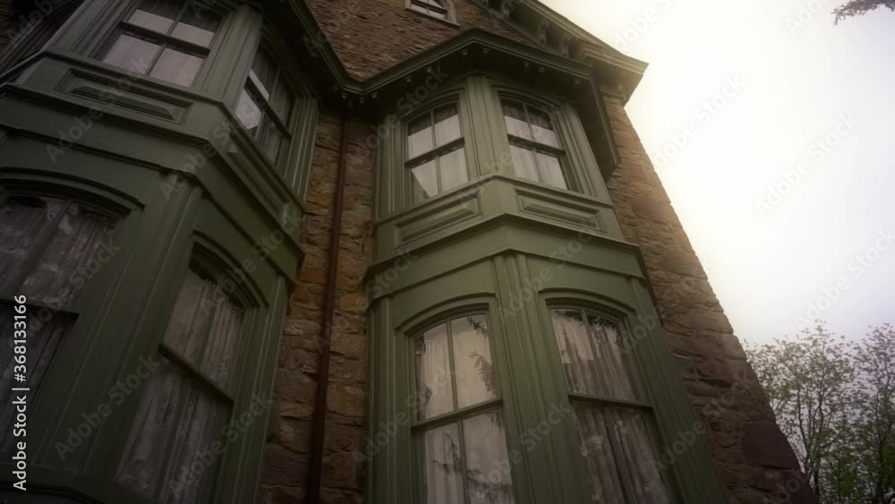 Handheld tilt up and then down of dark green bay windows of a brick rustic house in Pennsylvania Handheld tilt up and then down of dark green bay windows of a brick rustic house in Pennsylvania