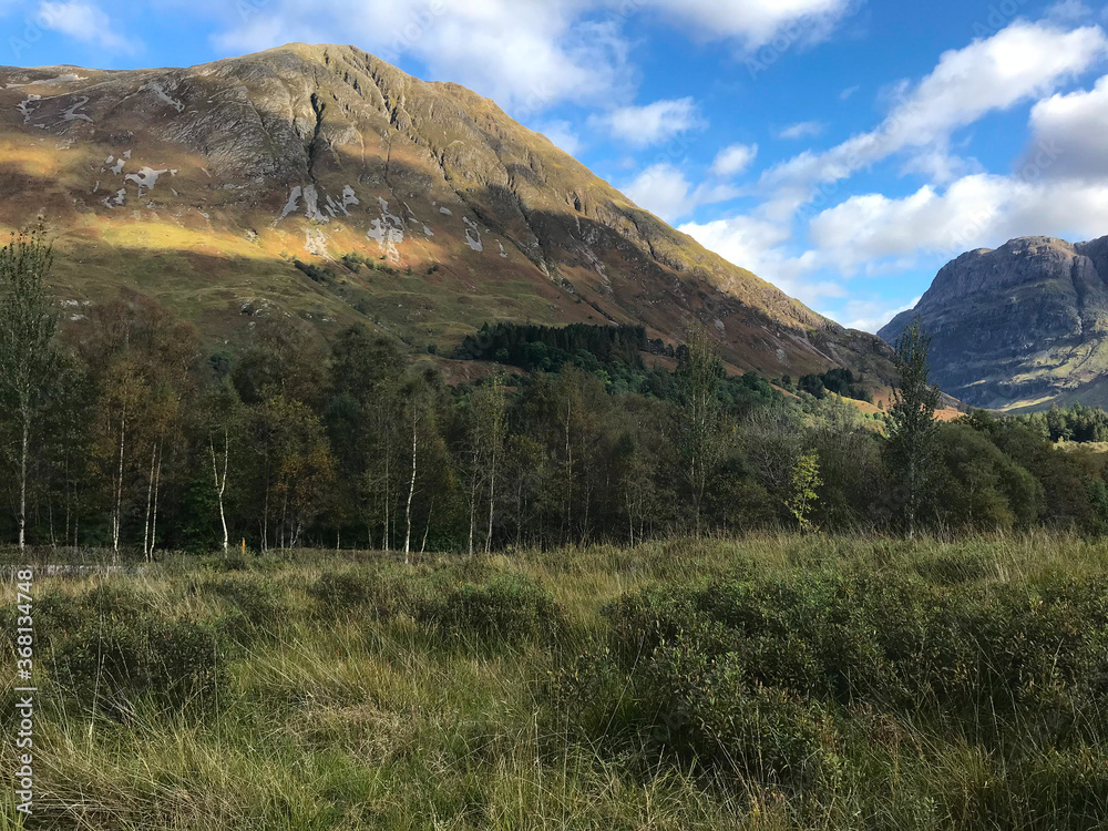 A scenic landscape view of a field with a beautiful mountain in the background - Glencoe