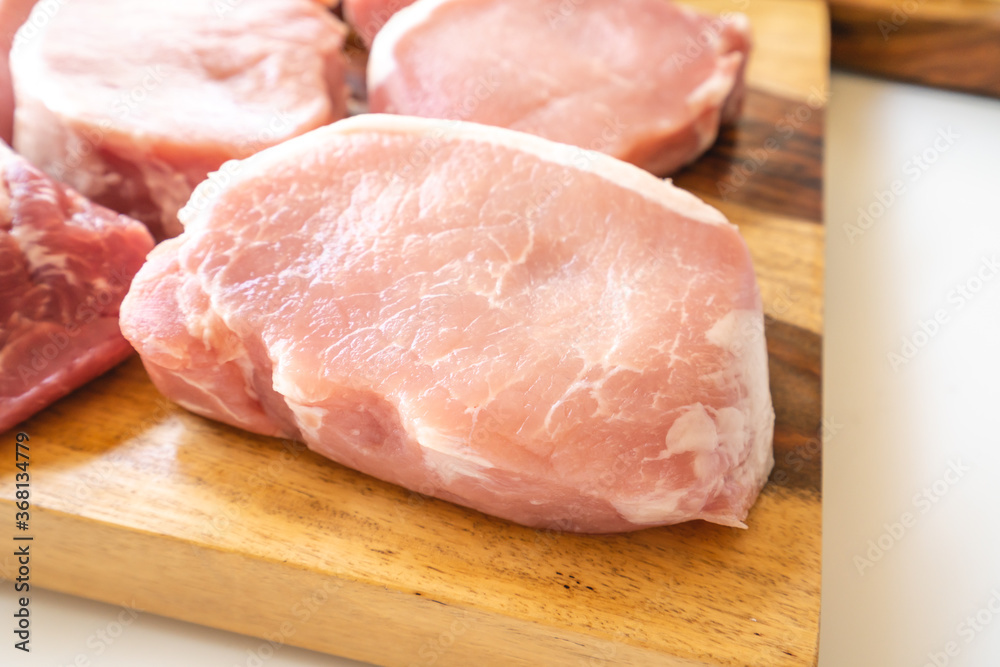 Boneless raw pork loin chops close up on wooden cutting board Boneless raw pork loin chops close up on wooden cutting board