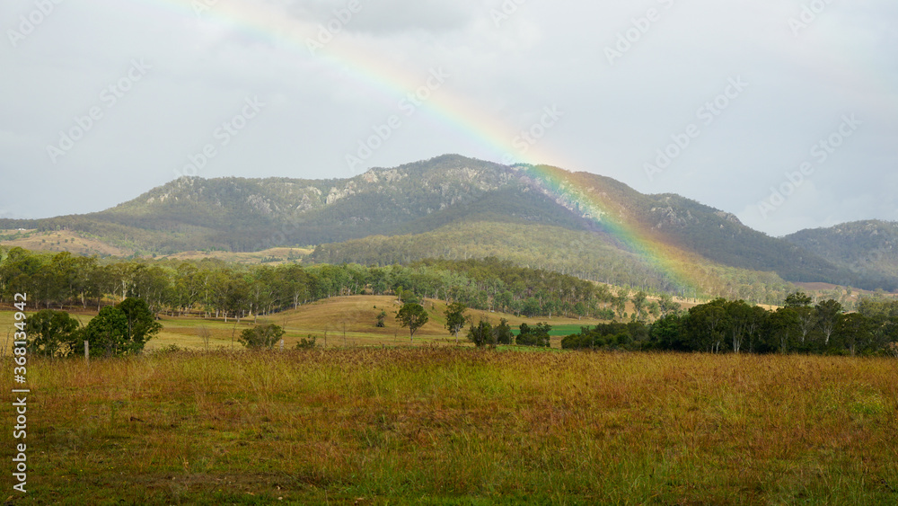 Rural landscape with rainbow over the mountain on a rainy day. Scenic Rim, Queensland, Australia.
