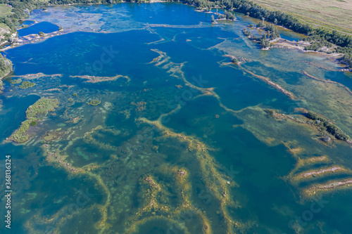 Aerial view of a shallow turquoise lake with a raised sandy bottom © alexkazachok