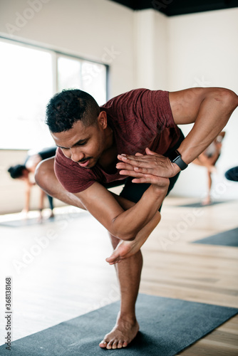 Man holding yoga pose in a studio class 