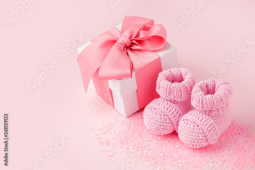 Close up of baby shoes, present gift box - sweetness and baby booties on pink background, first newborn party background, birthday, gift present giving concept, celebrate card