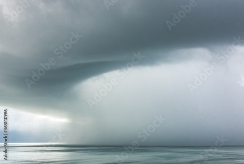 A rain storm in Daytona, Florida pours water over the Atlantic Ocean during a grey and overcast day by the beach.