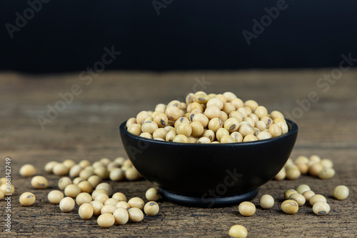 Raw soybeans in wooden bowl on wooden table background.