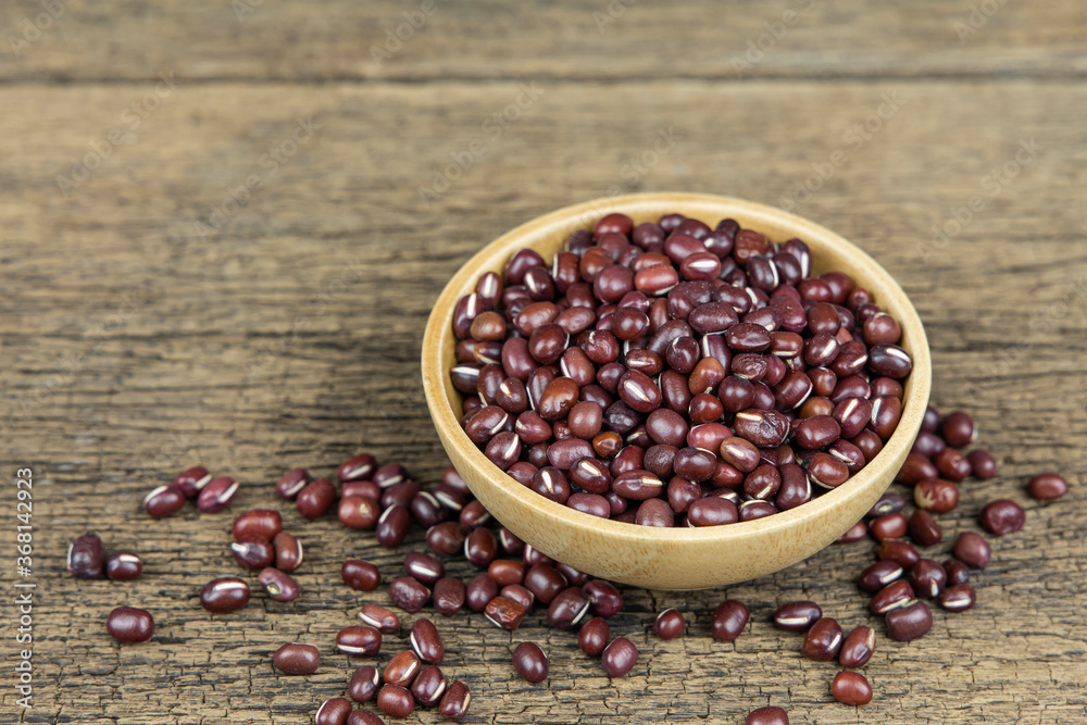 Raw red beans seed in wooden bowl on wooden table background.