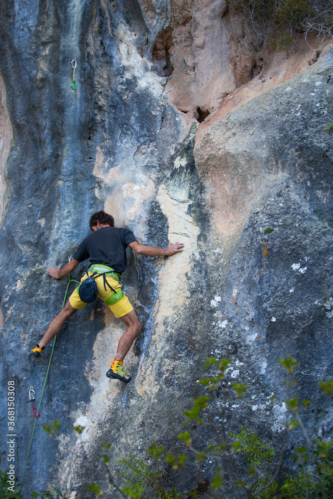 A strong man overcomes a difficult climbing route on a natural terrain. A strong man overcomes a difficult climbing route on a natural terrain.