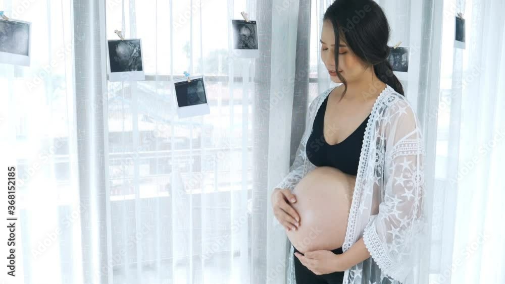 pregnant woman with ultrasound photo and pat her pregnant belly pregnant woman with ultrasound photo and pat her pregnant belly