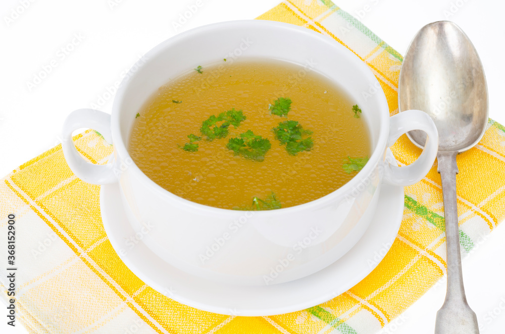 Transparent meat broth with herbs in white plate Transparent meat broth with herbs in white plate