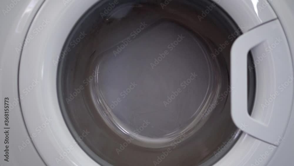 Close-up of a Laundry washing machine, spinning with dirty clothes Close-up of a Laundry washing machine, spinning with dirty clothes