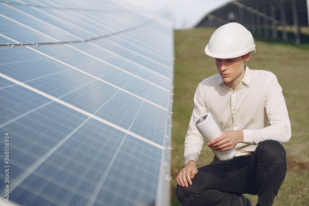 Portrait of client in white helmet at solar power station. Man in business suit.