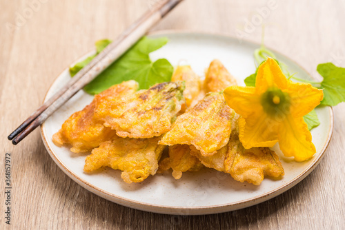 Crunchy fried pumpkin flowers on plate with chopsticks for eating, Edible flowers, Vegan snack