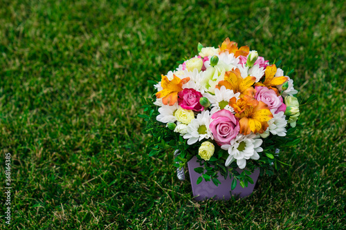 Fotografi bouquet of colorful flowers in hatbox on lawn. place for text.